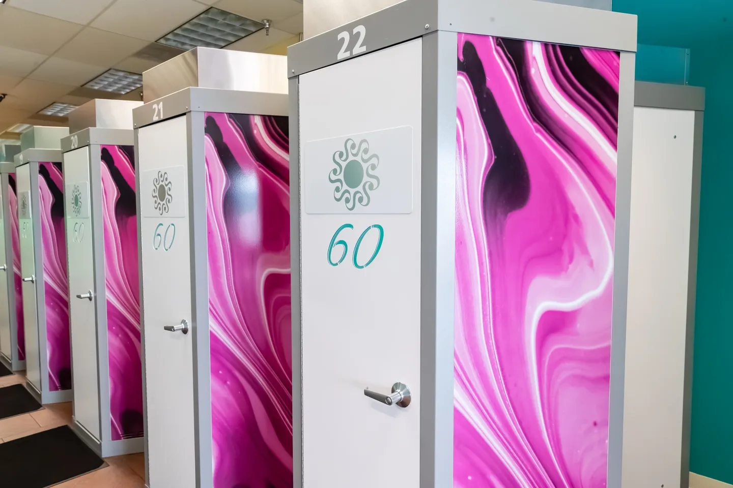 A row of pink and white toilets with numbers on them.